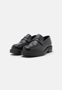 Mocassins en cuir noir au fini lisse, présentant un design à double sangle, un embout rond et une semelle basse et épaisse.
