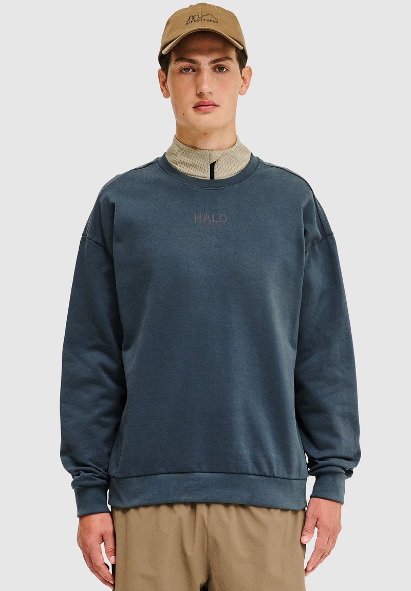 Ciemnoniebieska bluza z okrągłym dekoltem, ściągaczami przy mankietach i pasie. Posiada małe logo "HALO" w kontrastowym kolorze, wykonane z miękkiego materiału.