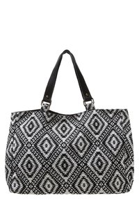 Svart och vit mönstrad tote-väska med ett geometriskt diamantmönster, tillverkad av tyg, med dubbla svarta läderhandtag och metalldetaljer.