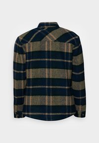 Koszula w kratę w kolorach ciemnoniebieskim, zielonym i beżowym. Posiada mankiety na guziki, kołnierzyk oraz klasyczny krój z długim rękawem.