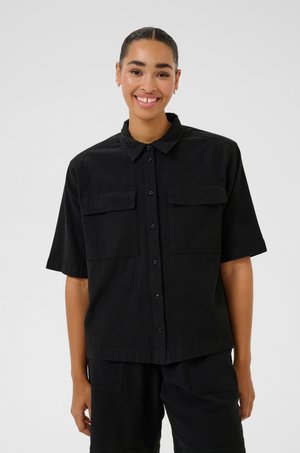 Maglietta nera a maniche corte realizzata in tessuto leggero, con chiusura a bottoni sul davanti e due tasche sul petto. Design casual con colletto classico.
