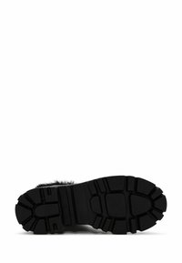 Suela de bota de goma negra, patrón de banda de rodadura resistente, superficie texturada y diseño de punta redondeada con pelo de acento en el borde superior.