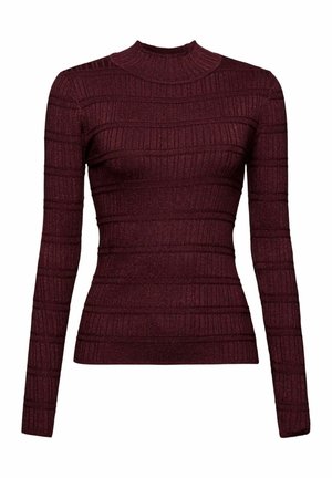 Femme portant une veste en cuir noire boutonnée, un pull bordeaux, une jupe midi à carreaux grise, des bottes en daim marron, tenant une pochette beige pliée.