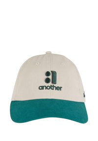 Casquette en coton beige avec une visière vert foncé. Présente un texte brodé "another" et un design stylisé. Coutures visibles et bouton sur le dessus.