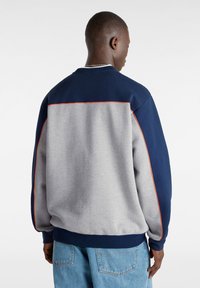 Sweatshirt med en färgblockdesign med marinblå axlar och en grå kropp. Pyntad med orange piping på sömmarna och ärmsluten.