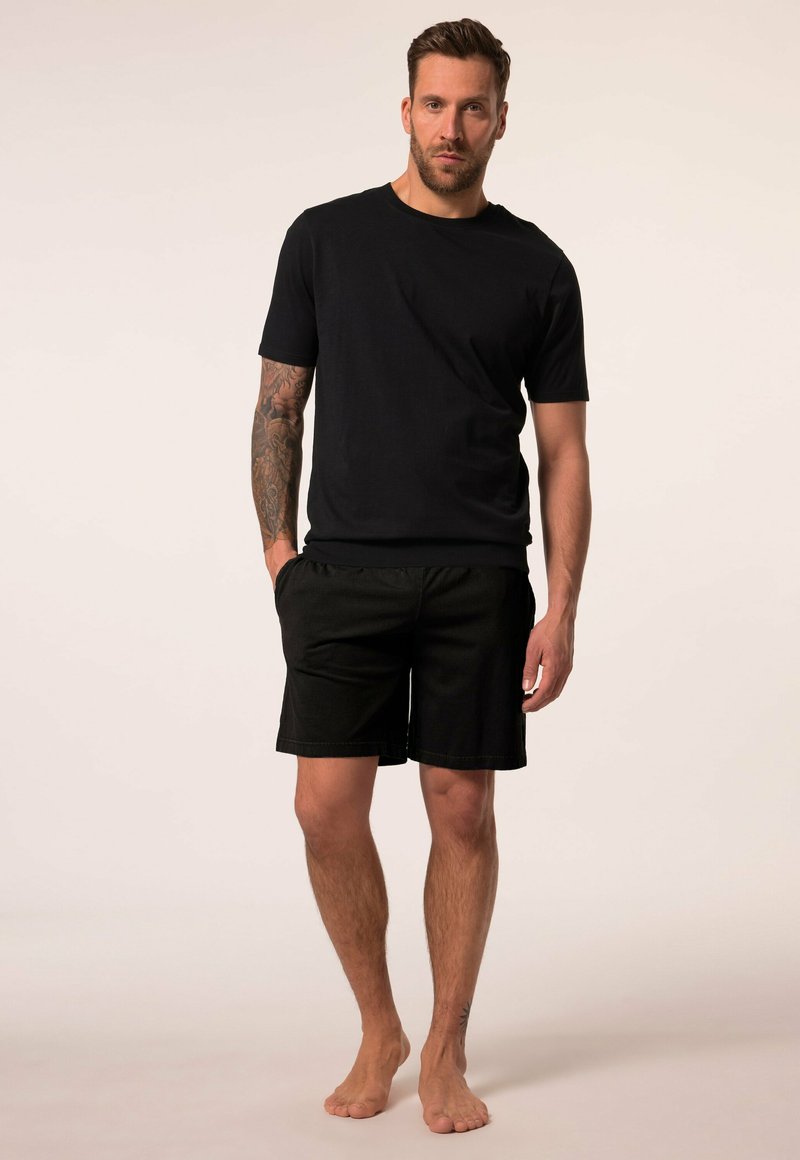 Zwarte katoenen T-shirt met korte mouwen, gecombineerd met zwarte shorts. De outfit heeft een eenvoudig, casual ontwerp zonder patronen of versieringen.