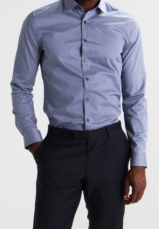 Lichtblauw overhemd met kleine, donkere geometrische patronen, lange mouwen, kraag en knoopsluiting aan de voorkant, gecombineerd met donkere broek.