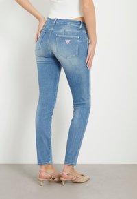 Tunna blå denimjeans med en blekt tvätt, som har en triangulär logopatch på bakfickan och en slät textur.