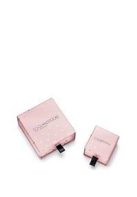 Des boîtes d'emballage roses avec un motif de points dorés, présentant un logo. Une grande boîte carrée et une petite boîte, toutes deux avec des languettes noires.