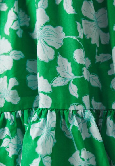 Vihreä mekko, jossa on valkoisia kukkakuosisia painatuksia, rypytetty helma, pehmeä kangaskuvio ja erottuvat suuret kukkakuviot kankaan pinnalla.