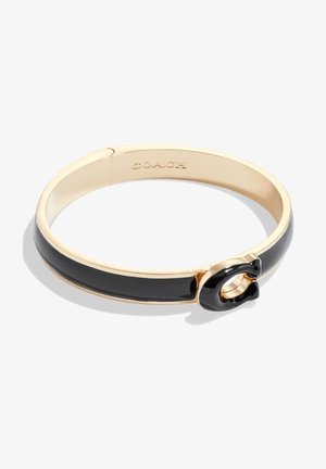Bracelet jonc doré avec incrustation d’émail noir et détail de fermoir "C" noir, « COACH » gravé à l’intérieur du bracelet.