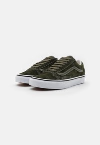 Baskets en suede vert avec semelles en caoutchouc blanches, comportant des accents noirs et des coutures contrastées, ainsi que des lacets plats pour un maintien sûr.