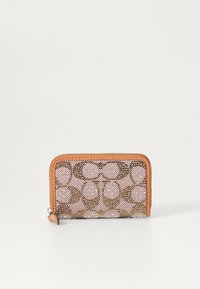 Portefeuille compact avec un design en maille rose, orné de motifs circulaires bruns et d'une garniture en cuir orange. Fermeture zippée avec un petit onglet.