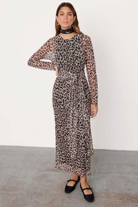 Šaty s leopardím potiskem, dlouhý rukáv a zavinovací design. Průhledná tkanina, zvýrazněný pas a splývavá sukně. V kombinaci s černými botami a chokerem.