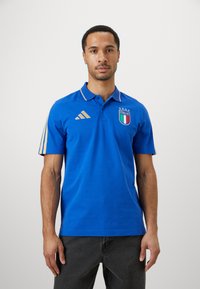 Μπλε πόλο μπλούζα με χρυσές λεπτομέρειες, έμβλημα Ιταλίας, κολάρο με δύο κουμπάκια και τρεις ρίγες στα μανίκια. Φτιαγμένη από αε ventilated ύφασμα.