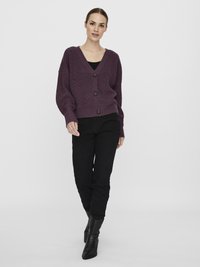 Purple ribbed cardigan with a V-neck, four buttons, and long sleeves, paired with black fitted pants and pointed black boots.
