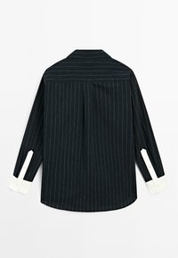 Black striped long-sleeve shirt with a pointed collar and white cuffs. Features vertical pinstripes and a back pleat for added movement.