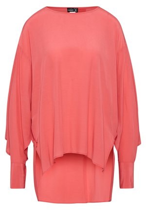 Blouse corail rose à manches longues, coupe ample, col bateau et ourlet asymétrique, avec larges poignets et tissu doux et fluide.