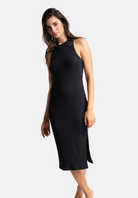 Robe midi sans manches en tricot côtelé noir, avec un col haut et une fente sur le côté, présentant un design ajusté et une texture douce.