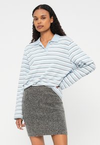 Vaaleansininen raidallinen pitkähihainen poolopaita, jossa on kaulus, yhdistettynä istuvaan harmaaseen villahameeseen. Pehmeä rakenne, kolme nappia kaula-aukossa.