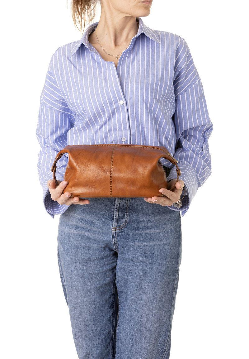 Borsa in pelle marrone con forma arrotondata, chiusura con zip e doppi manici; texture liscia con dettagli di cucitura visibili.