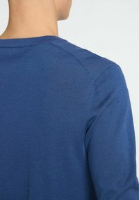 Blå stickad tröja med rund halsringning och slät textur. Tyget har ett lätt utseende med ett subtilt ribbat mönster längs sömmarna.