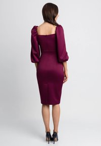 Burgundowa dopasowana sukienka z bufkami, kwadratowym dekoltem i zamkiem błyskawicznym z tyłu. Wykonana z gładkiego materiału, z rozporkiem u dołu.