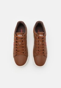 Bruna lädersneakers med runda tår, vita gummisulor och bruna snören. Har Levi's logotyp på tungan och sidan.