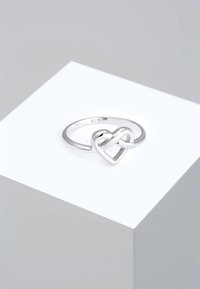 Sterling sølvring med et snoet hjerte-design. Markeret "925" for sølvrenhed, med en glat, poleret finish.