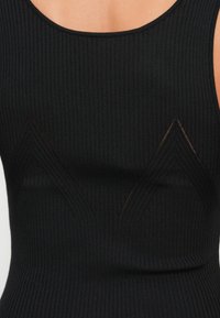 Μαύρο ριμπ αμάνικο τοπ με στρογγυλή λαιμόκοψη. Διαθέτει δύο τριγωνικά κοψίματα στο στήθος, δημιουργώντας ένα υφασματικό σχέδιο.