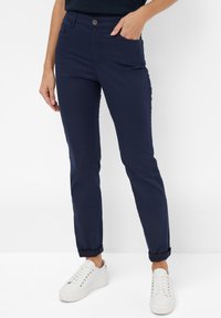 Donkerblauwe broek van zachte, rekbare stof; slim fit met opgerolde pijpen; heeft zijzakken en een enkele knoopsluiting.