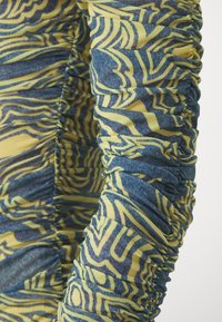 Long-sleeve top featuring a yellow and blue abstract pattern with gathered, textured fabric for a fitted appearance.