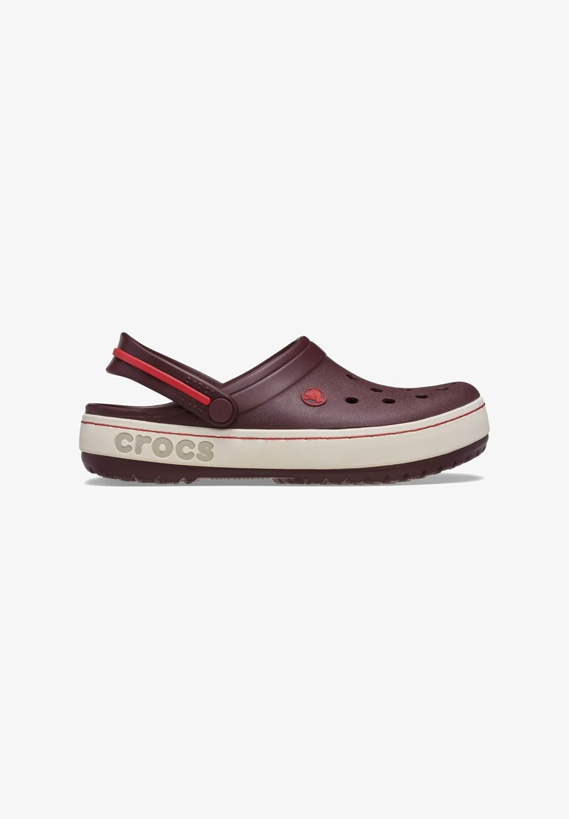 Sabot Crocs bordeaux avec des trous de ventilation, une semelle intermédiaire blanche avec le logo "crocs", et une bride de talon ajustable accentuée de rouge.