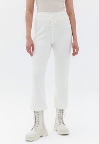 Witte geribde joggers met een elastische tailleband en trekkoord. Gecombineerd met witte veterschoenen met dikke zolen.