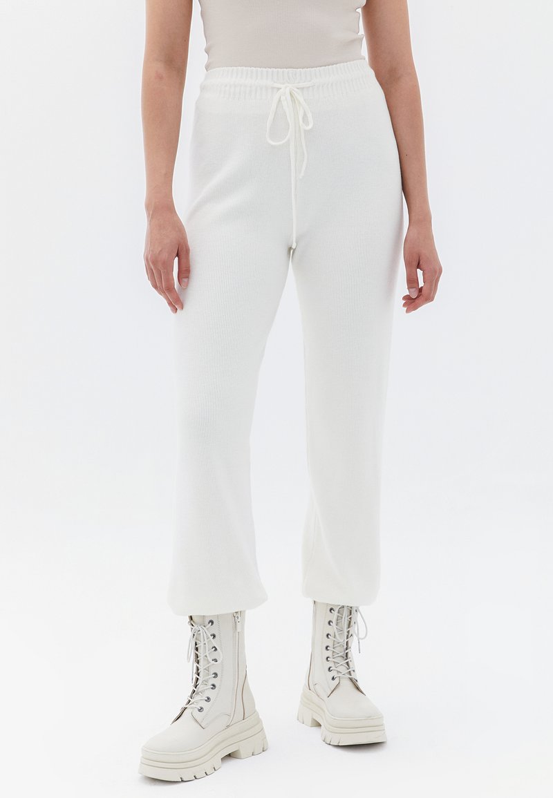 Witte geribde joggers met een elastische tailleband en trekkoord. Gecombineerd met witte veterschoenen met dikke zolen.