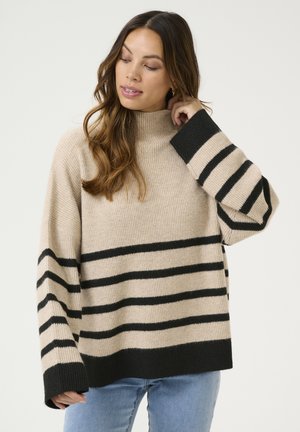 Maglione beige chiaro con righe nere, collo alto, texture a coste, vestibilità ampia e maniche larghe. Il materiale sembra morbido e accogliente.