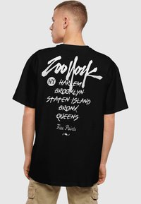 T-shirt noir arborant un texte blanc en gras. Le dos affiche "Zoo York" ainsi que des noms de lieux de New York dans différentes polices et tailles.