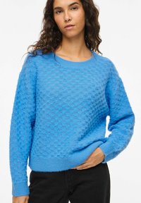 Pull bleu tricoté avec un motif texturé, col rond et manches longues. Tissu doux avec poignets et ourlet côtelés.