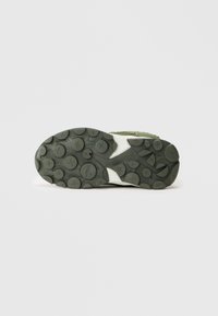 Suola di sneaker KangaROOS verde con battistrada circolare caratterizzato da motivi a "X" e un logo di canguro al centro.