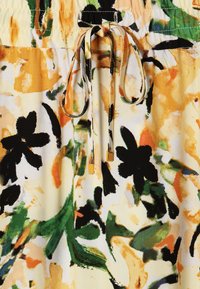 Țesătură cu print floral în nuanțe de galben, portocaliu, verde și negru, având un elastic la talie și un șnur de legat cu accente aurii.