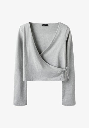 Grå långärmad wrap-top i mjukt, stretchigt material. Har en v-ringning och knyt-detalj på sidan. Kortsiktig design.