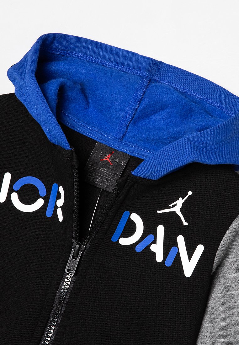 Sudadera con cremallera negra con forro azul en la capucha, mangas grises y texto "JORDAN" en azul y blanco con el logo Jumpman blanco en el pecho.