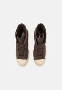 Sneakers alte in suede marrone con punta e lacci in gomma crema. Design minimalista, con collo imbottito e logo sulla soletta.