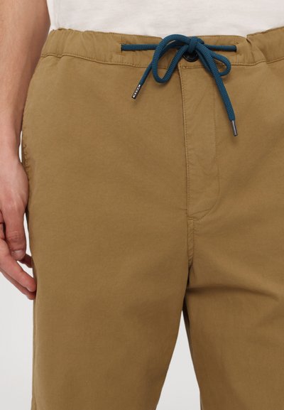 Beige shorts made of lightweight fabric with an elastic waistband, featuring a blue drawstring and small silver hardware accents.