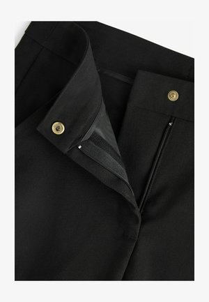 Juodos kelnės su lygiu paviršiumi, turinčios užtrauktuką, auksinį mygtuką ir platų juosmenį, užtikrinantį tvirtą prigludimą.