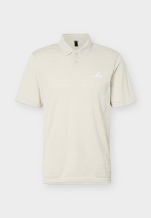 Tricou polo bej cu mâneci scurte, două nasturi și logo-ul Adidas alb pe pieptul stâng.