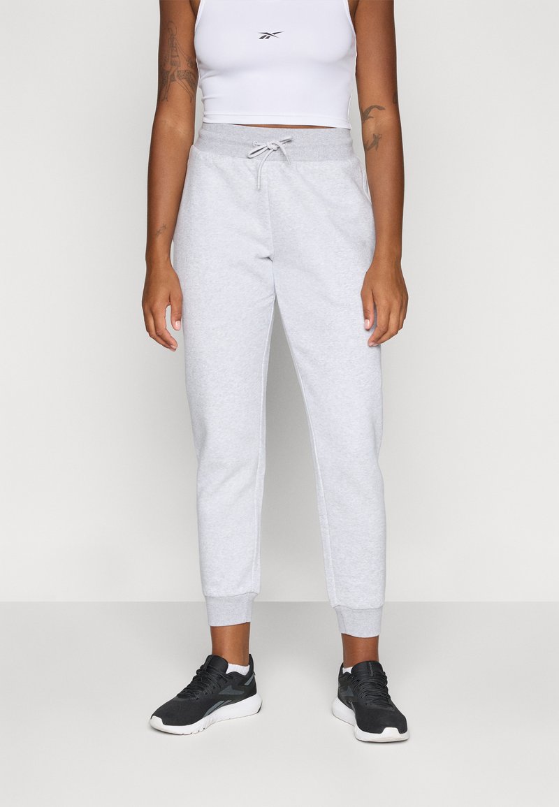 Ljusgrå sweatpants med elastisk midja som har dragsko, ribbade manschetter och en avsmalnande passform, tillsammans med svarta sportskor.