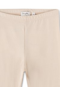 Beige Leggings aus weichem, elastischem Material mit einem elastischen Bund und ohne sichtbare Nähte, die für Komfort und Bewegungsfreiheit entworfen wurden.