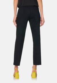 Zwarte broek met patroon in een slim fit, gemaakt van een gestructureerde stof met rechte pijpen, gecombineerd met gele blokhak sandalen.