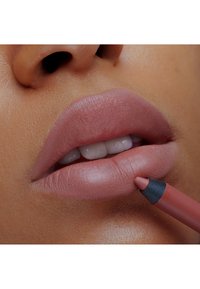 Matte nudefarget leppestift blir påført med en leppeblyant. Blyanten har en svart tupp, og leppene har en jevn, teksturert finish.